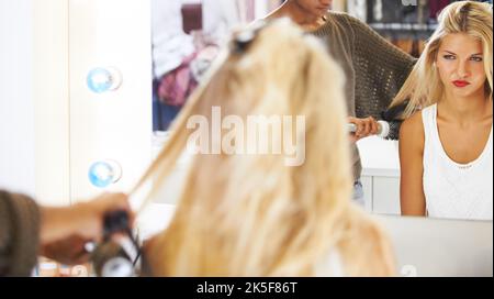 Sie zeigt ihre wahren Farben - Diva. Hochnäsige junge Frau, die ihre Haare von einem Stylisten machen lassen. Stockfoto