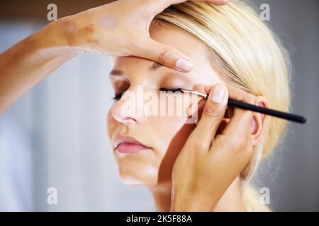 Für einen vielseitigen Make-up-Look. Hübsche junge Frau, die ihr Make-up von einem Stylist aufgetragen hat. Stockfoto