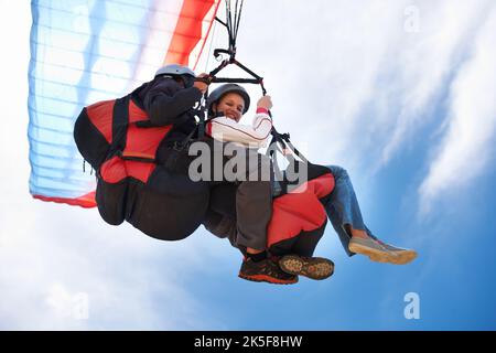 Leicht wie Luft. Low-Angle-Ansicht von zwei Menschen tun Tandem Paragliding l. Stockfoto