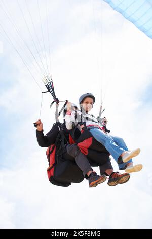 Ich wünschte, das würde nie enden. Zwei Leute, die Tandem-Paragliding machen und nach unten schauen. Stockfoto