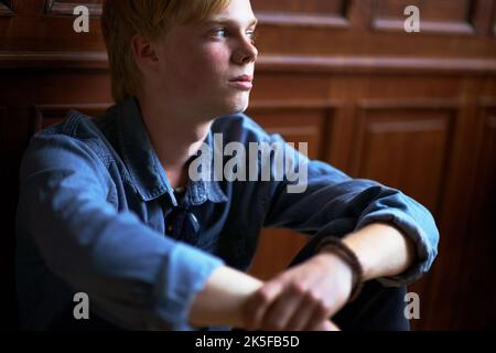 Über seine Zukunft nachdenken. Nachdenklicher und hübscher junger blonder Kerl mit sehr blauen Augen. Stockfoto