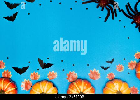 Halloween-Konzept, Scary Lächeln Kürbis und Spinne mit Fledermäusen sind auf hellblauem Hintergrund angeordnet. Stockfoto