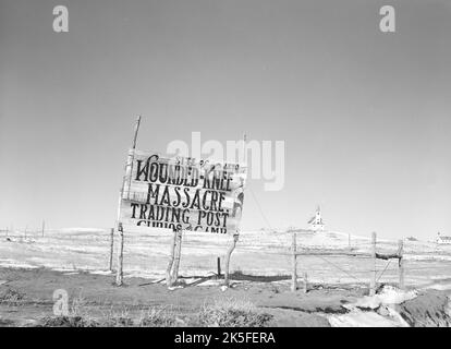 John Vachon - Verwundete Knie Massaker Trading Post Signage und Heilige Herz katholische Kirche in Wounded Knie, South Dakota - c1940 Stockfoto