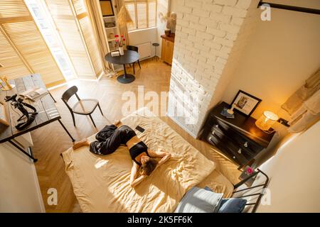 Frau, die sich im Studio-Apartment entspannt Stockfoto