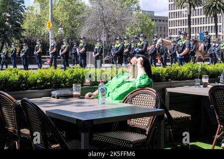 Melbourne, Australien, 8. Oktober 2022. Eine Frau sitzt in einem Café mit einer Polizeilinie in der Nähe während Pro-Choice-Gegen-Kundgebungen, um gegen den Protest zu protestieren, der heute von der Abgeordneten des Landtags Bennie Finn in der Nähe des landtags organisiert wurde. Kredit: Michael Currie/Geschwindigkeit Medien/Geschwindigkeit Medien Gutschrift: Geschwindigkeit Medien/Alamy Live Nachrichten Stockfoto