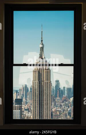 New York City Manhattan, Blick im Sommer auf das Empire State Building, eingerahmt vom Fenster eines benachbarten Wolkenkratzers, Manhattan, New York City, NYC, USA Stockfoto