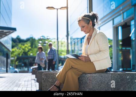 Attraktive Geschäftsfrau, die in einer modernen Stadt mit einem Tablet arbeitet. Stockfoto
