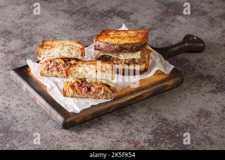 Das patty Melt Sandwich hat ein Burger-Patty, das mit geschmolzenem Schweizer Käse, karamellisierten Zwiebeln und geröstete Scheiben Roggenbrot in der Nähe auf dem hölzernen bo bedeckt ist Stockfoto