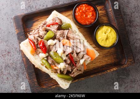 Köstliches italienisches Rindfleisch-Sandwich in Chicago mit langsam gekochtem Rindfleisch und Giardanarra-Nahaufnahme auf einem Holztablett auf dem Tisch. Horizontale Ansicht von oben Stockfoto