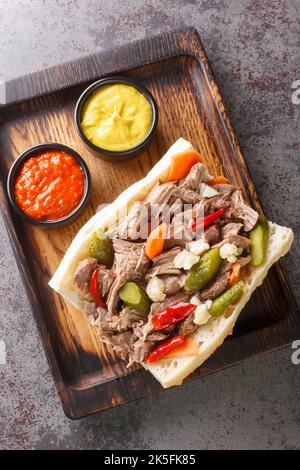 Chicago Style Italienisches Rindfleisch Sandwich Nahaufnahme auf dem Holztablett auf dem Tisch. Vertikale Draufsicht von oben Stockfoto