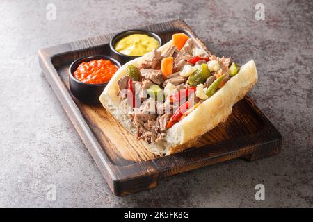 Köstliches italienisches Rindfleisch-Sandwich in Chicago mit langsam gekochtem Rindfleisch und Giardanarra-Nahaufnahme auf einem Holztablett auf dem Tisch. Horizontal Stockfoto