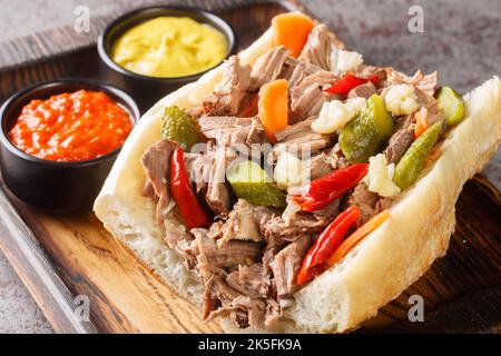 Hausgemachtes italienisches Rindfleisch-Sandwich von Chicago mit Giardanarra-Nahaufnahme auf dem Holztablett auf dem Tisch. Horizontal Stockfoto