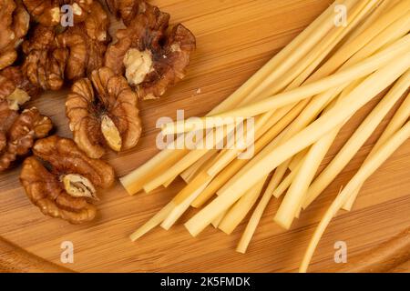 Verschiedene Sorten von Käse, Walnusskernen und geräucherten Wachteleiern auf einer Holzoberfläche. Stockfoto