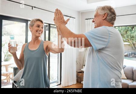 High Five, Erfolg oder Senioren paar Fitness, Training oder Bewegung im Wohnzimmer zu Hause. Lächeln, glücklich oder Sport Teamarbeit Geste für den Ruhestand Stockfoto