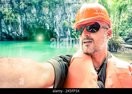 Gutaussehender Mann, der Selfie in den unterirdischen Flusshöhlen von Puerto Princesa nimmt - Reisekonzept in Palawan Philippinen - warme Grüntöne mit Fokus auf Stockfoto