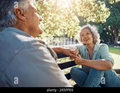 Ältere Menschen, Paare und glücklich auf der Bank im Garten für Gespräche, Bindung und Glück von Bäumen im Sommer. Mann, Frau und Ruhestand zeigen Liebe, entspannen Stockfoto