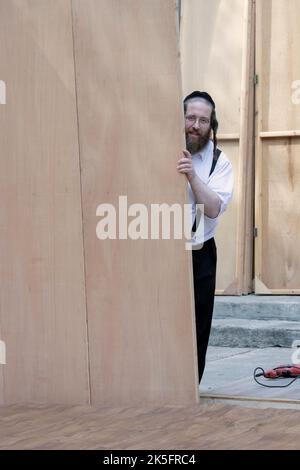 In Vorbereitung auf den Feiertag von Sukkos baut ein orthodoxer Jude eine Sukkah. In Williamsburg, Brooklyn, New York City. Stockfoto