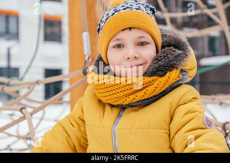 An einem verschneiten Wintertag spielt das Kind auf dem Spielplatz. Stockfoto