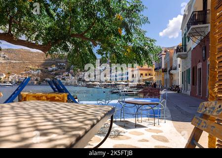 Panoramablick auf die kleine Oase der Insel Symi. Dorf mit Street Cafe und bunten Häusern auf Felsen. Stockfoto