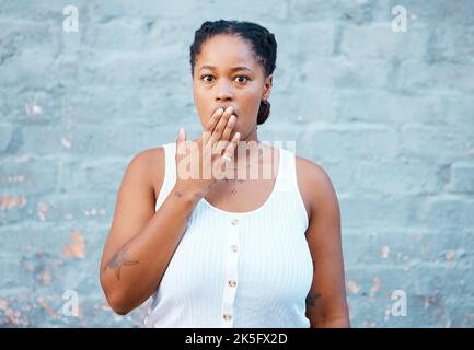 Schockierte schwarze Frau, Hand und Sorge in der Stille für Geheimnis vor einer Wand Hintergrund. Porträt einer afroamerikanischen Frau, die den Mund bedeckt Stockfoto