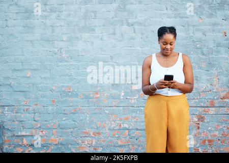 Schwarze Frau, Mode und Telefon an einer Scheinwand in der nigrischen Stadt für Marketing-, Werbe- oder Verkaufsförderungs-Mockup. Lächeln, glücklich oder Trend Stockfoto