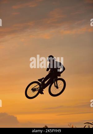 Mountainbike, Radfahrer und Fitness springen bei Sonnenuntergang in Colorado Landschaft Natur in Training, Bewegung oder Training. Gefahrenrisiko, extremer bmx-Sport oder Stockfoto