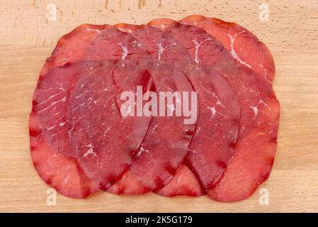 Bresaola Scheiben, italienische getrocknete Rindersalami aus Valtellina auf Holzhintergrund Stockfoto