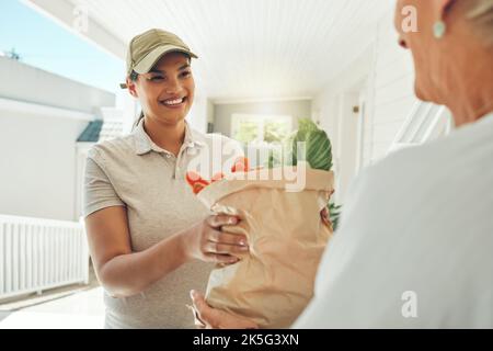 Frau, Lächeln und Lebensmittelzustellung für alte Frau aus dem Supermarkt. Gesundheit, Einkaufen und weiblich mit älteren Dame Kunde am Hauseingang, gesund Stockfoto