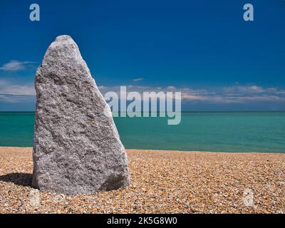 Ein großer, 2m Jahre langer, grauer Stein am Kiesstrand von Walmer, Deal, Kent, Großbritannien. Aufgenommen an einem sonnigen Tag mit blauem Himmel und türkisfarbenem Meer. Stockfoto