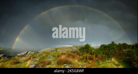 Farbenfroher Regenbogenbogen, Farbspektrum, landschaftlich reizvolle Landschaft, unheilvoll stürmisch bewölkt regnerisch - Cow & Calf Rocks, Yorkshire, England, UK. Stockfoto