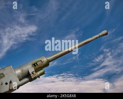 Der Lauf einer 1942 40mm Bofors Pistole zeigt nach oben zu einem blauen Himmel mit hellweißen Wolken. Dies war ein schwedisch gefertigtes Flak-Geschütz. Stockfoto