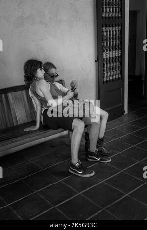 Eine Graustufenaufnahme eines Paares, das auf einer Bank im San Diego California Park sitzt Stockfoto