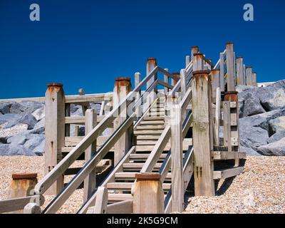 Verwitterte Holztreppen ermöglichen den Zugang zum Strand von Camber Sands in East Sussex an der Südküste Großbritanniens. Aufgenommen an einem sonnigen Tag im Sommer. Stockfoto