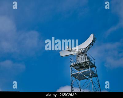 Eine weiße Radarschale, die auf einem Stahlrahmenturm montiert ist. Aufgenommen an einem sonnigen Tag im Sommer. Stockfoto
