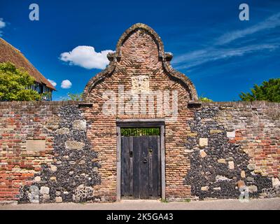 Ein altes Holztor, das von einem Bogen aus rustikalem Mauerwerk und Stein auf beiden Seiten umgeben ist. Auf der linken Seite befindet sich eine Gedenktafel mit der Aufschrift „Kings Lodging“ Stockfoto