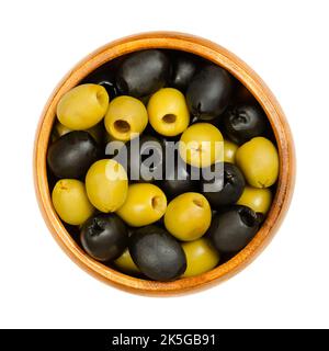 Grüne und schwarze Oliven, Hojiblanca, in einer Holzschale entsteint. Europäische Oliven, Olea europaea. Beliebte Tafeloliven mit einem geringeren Ölgehalt. Stockfoto