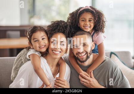 Glücklich, lächelnd und Porträt einer interrassischen Familie, die zu Hause auf einem Sofa im Wohnzimmer sitzt. Glück, Liebe und Adoptiveltern verbinden sich Stockfoto