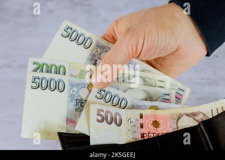 Zählung der tschechischen Krone CZK in der Brieftasche des Mannes, der die tschechischen Kronen-Banknoten hält Stockfoto