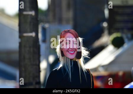 Cheddar, Großbritannien. 08. Oktober 2022. Eine Person mit Freunden wird in der Cheddar Gorge in der Nähe von Geschäften gesehen, die eine LIZ-TRAVERSEN-Maske auf ihrem HINTERKOPF trägt. Bildquelle: Robert Timoney/Alamy Live News Stockfoto