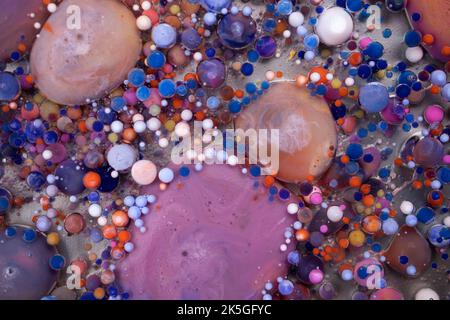 Acrylfarbe Kugeln abstrakte Textur. Leuchtende Farben fließendes Tapetendesign. Violette, blaue, rosa und gelbe Flüssigkeiten mischen sich. Stockfoto