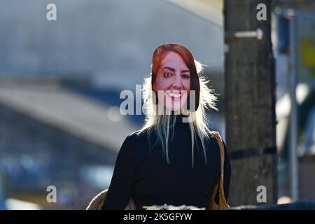 Cheddar, Großbritannien. 08. Oktober 2022. Eine Person mit Freunden wird in der Cheddar Gorge in der Nähe von Geschäften gesehen, die eine LIZ-TRAVERSEN-Maske auf ihrem HINTERKOPF trägt. Bildquelle: Robert Timoney/Alamy Live News Stockfoto