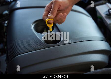 Der Fahrer überprüft den Ölstand im Fahrzeug Stockfoto