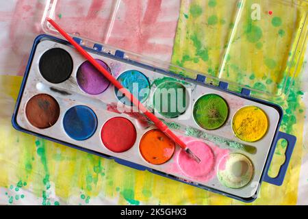 Aquarellfarbe mit Spuren der Verwendung in Karton und Pinsel isoliert auf weißem Hintergrund. Stockfoto