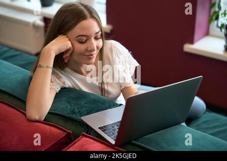 Zufriedener Telearbeiter, der in Innenräumen an einem tragbaren Computer arbeitet Stockfoto