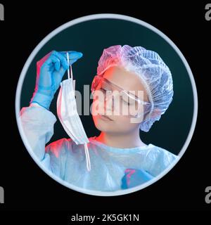 Persönlicher Schutz. Quarantänehygiene. Prävention von Krankheiten. Kopfbild der betroffenen Ärztin in blauen psa-Handschuhen mit Schutzbrille, die das gebrauchte Gesicht hält Stockfoto