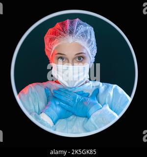 Shocked surgeon. Medic portrait. Unbelievable discovery. Portrait of speechless disturbed female doctor in blue ppe face mask gloves with hands at che Stockfoto