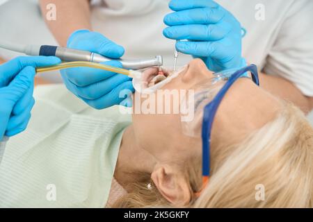 Elegante Frau während des Prozesses Zahnpflege in der medizinischen Praxis Stockfoto
