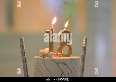 Eine Nahaufnahme eines Geburtstagstortes mit brennenden Kerzen. 18.-jähriges Jubiläum. Stockfoto