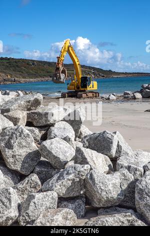 Mechanische Bagger auf einer Baustelle die Reparatur von Küstenverteidigungen und Meeresmauern mit Gesteinen aus einem Steinbruch nach dem Anstieg des Meeresspiegels verursachte Erosion und d Stockfoto