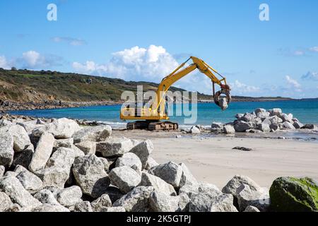 Mechanische Bagger auf einer Baustelle die Reparatur von Küstenverteidigungen und Meeresmauern mit Gesteinen aus einem Steinbruch nach dem Anstieg des Meeresspiegels verursachte Erosion und d Stockfoto